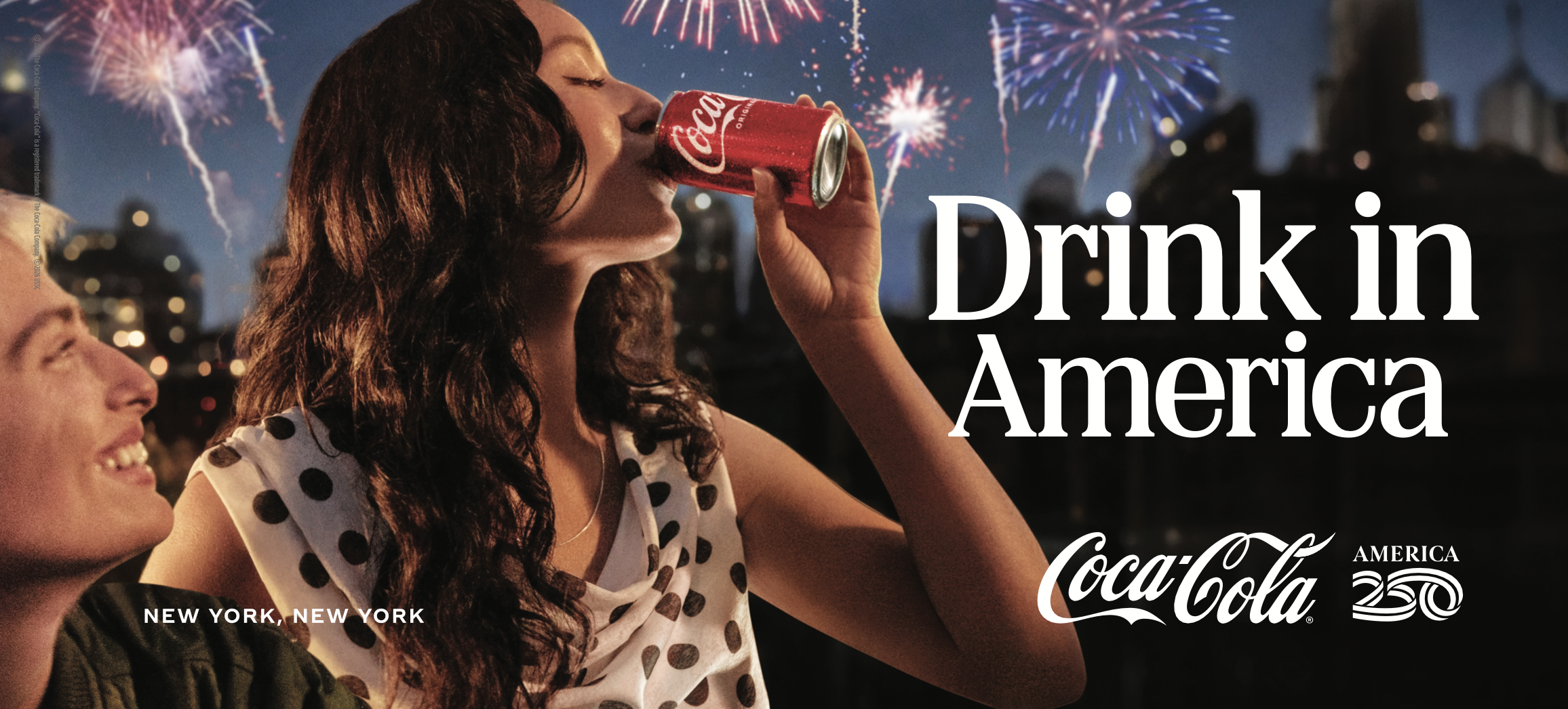 Woman drinking a can of Coca-Cola. Fireworks and city skyline in background. 