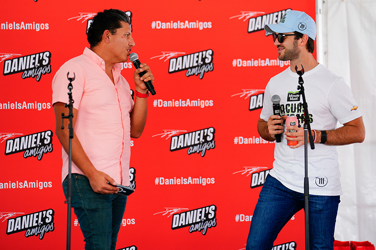 Daniel Suarez holding a can of Aguas Frescas while speaking at an event