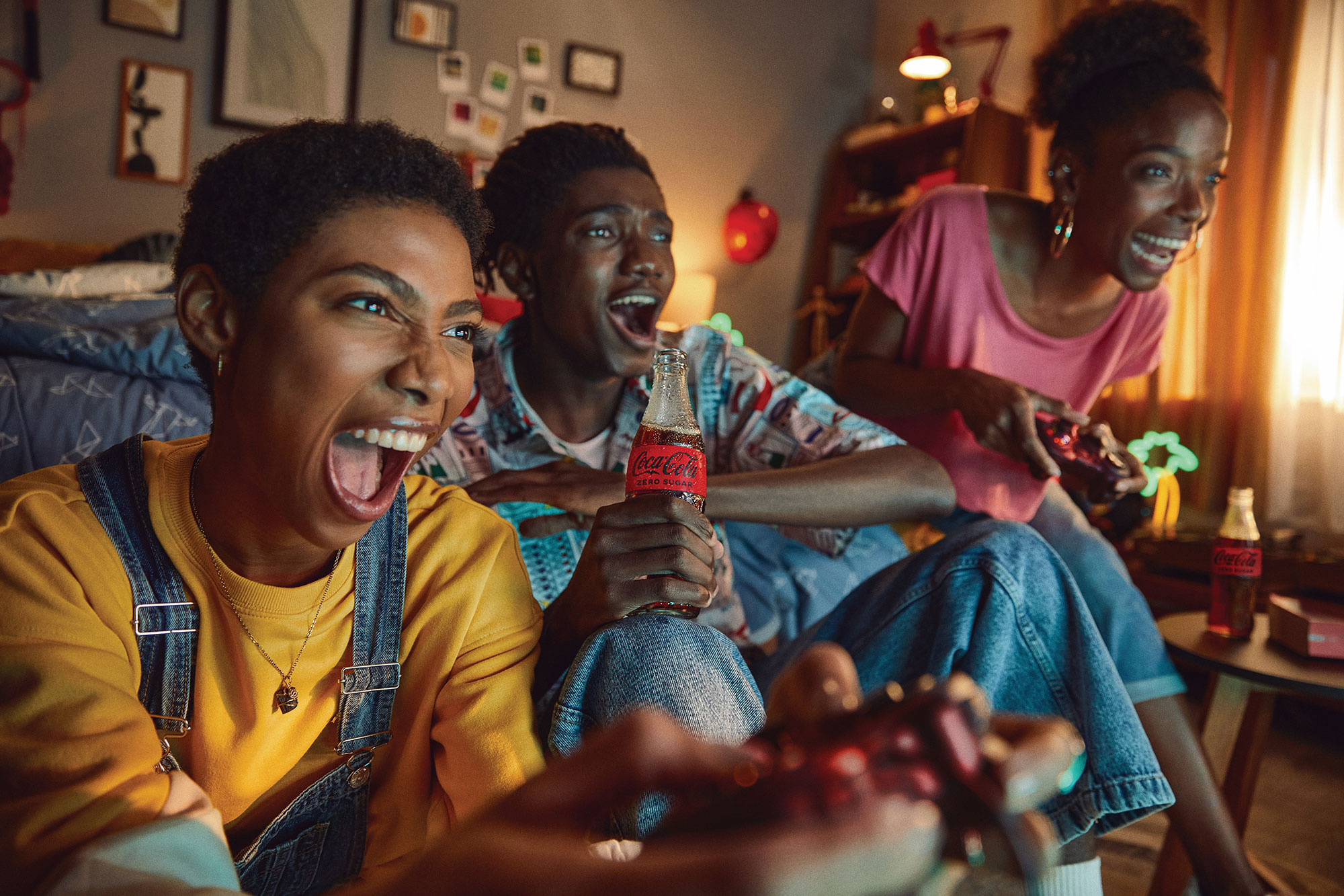 Three friends gaming and drinking bottles of Coca-Cola Zero Sugar