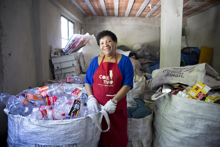 Woman in apron recycling plastic Coca-Cola bottles