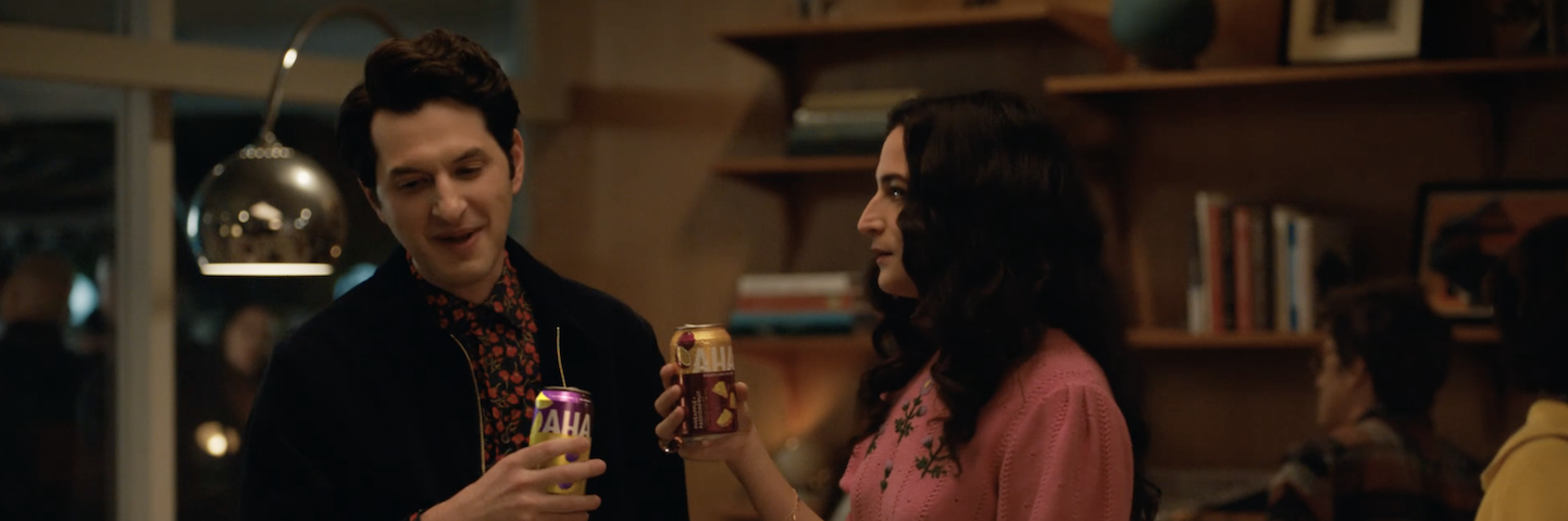 Ben Schwartz and Jenny Slate drink AHA at a party. 