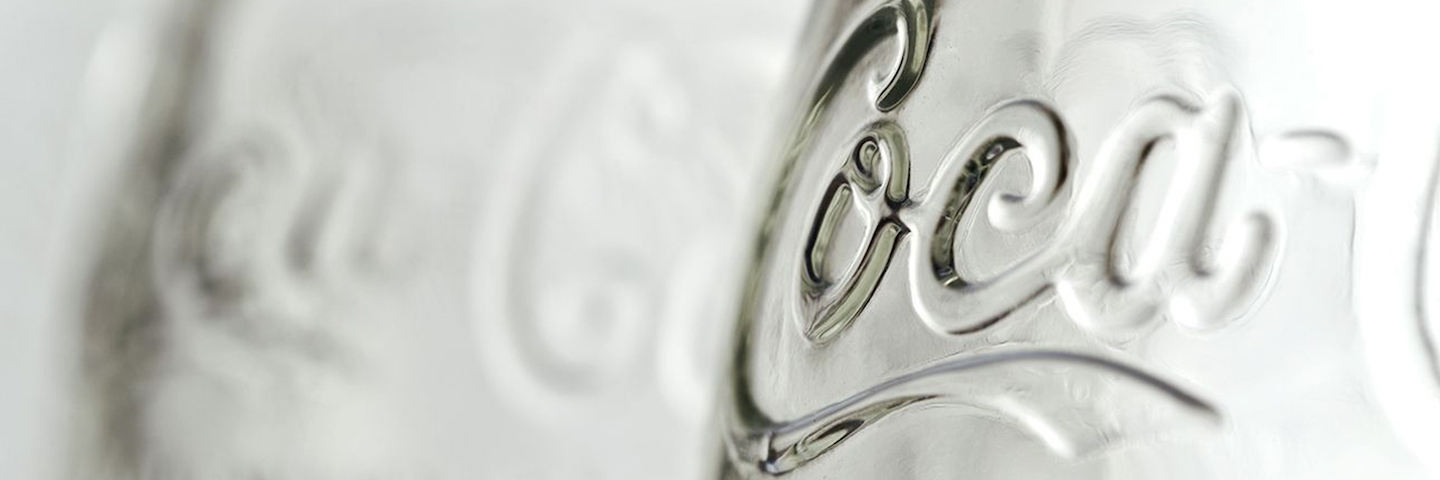 Close-up shot of a clear glass Coca-Cola bottle A close-up image of a clear, glass Coca-Cola bottle