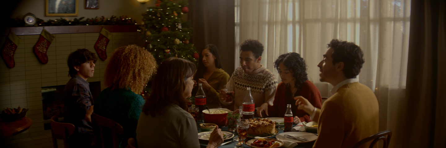 Coca-Cola Holiday Dinner people sit around a dinner table eating and talking