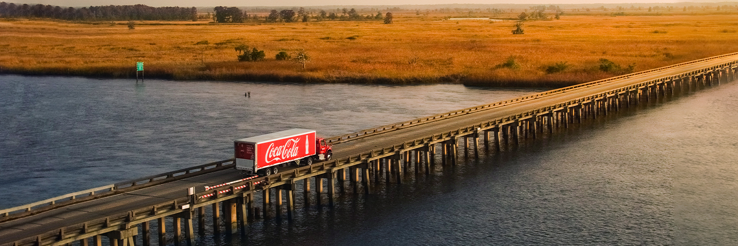 A Coca Cola Semi Truck Driving Across a Bridge Over Water A Coca-Cola Semi Truck Driving Across a Bridge Over Water