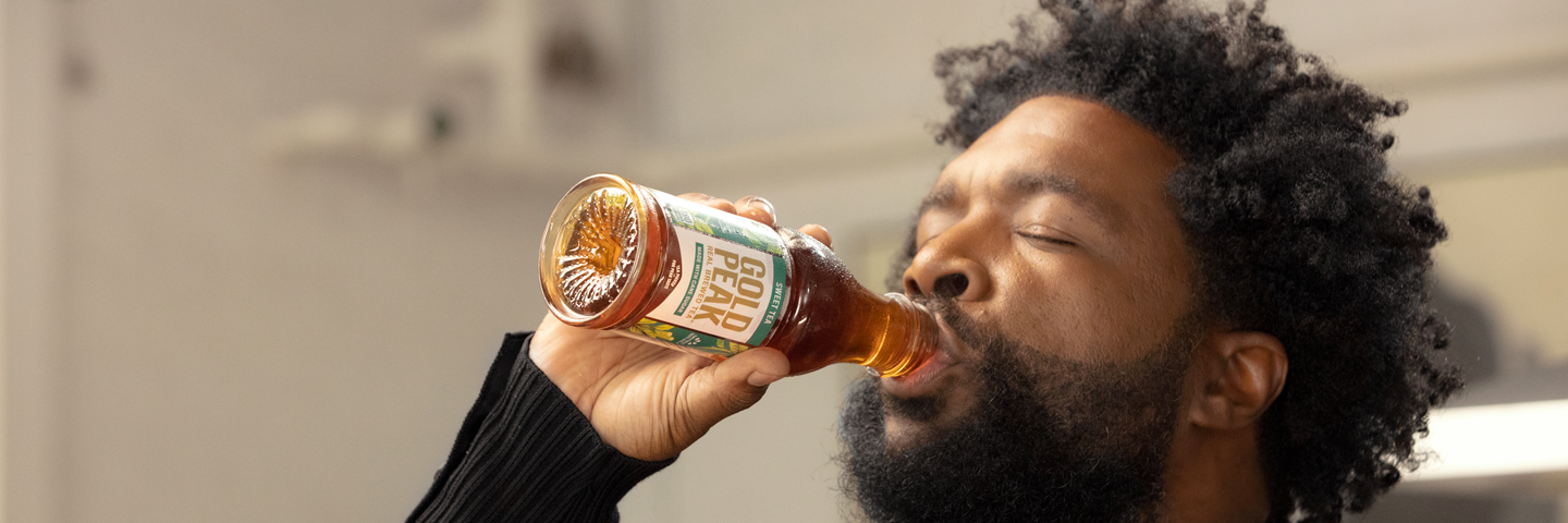 Man drinking a bottle of Gold Peak Tea Man drinking a bottle of Gold Peak Tea
