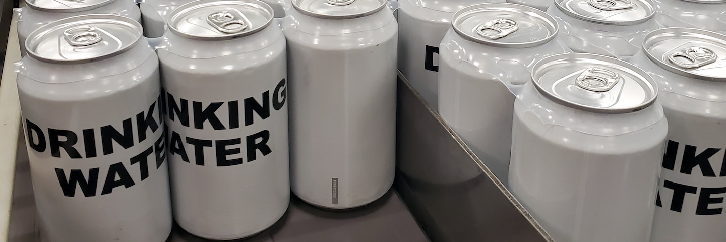 White, non-branded cans with "Drinking Water" written in black text