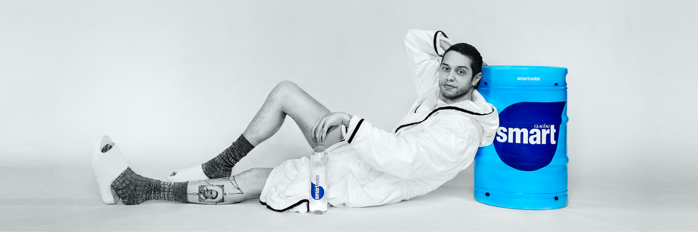 Pete Davidson leans back on smartwater beverage cooler while holding a bottle of smartwater Comedian Pete Davidson leans on smartwater branded cooler while holding a bottle of smartwater