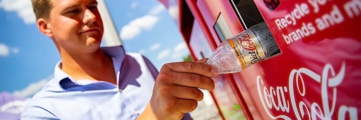 Man recycling bottle in Coca-Cola recycling bin.