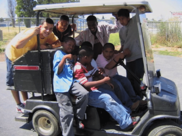 Fellow 2004 Scholars Mike Woodward (upper left) and Samuel (upper middle) with students in a soon-to-be souped-up golf cart.
