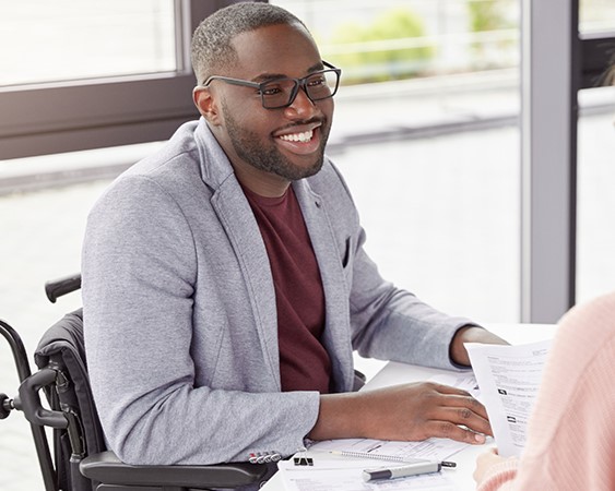 A man in a wheelchair is talking with a colleague