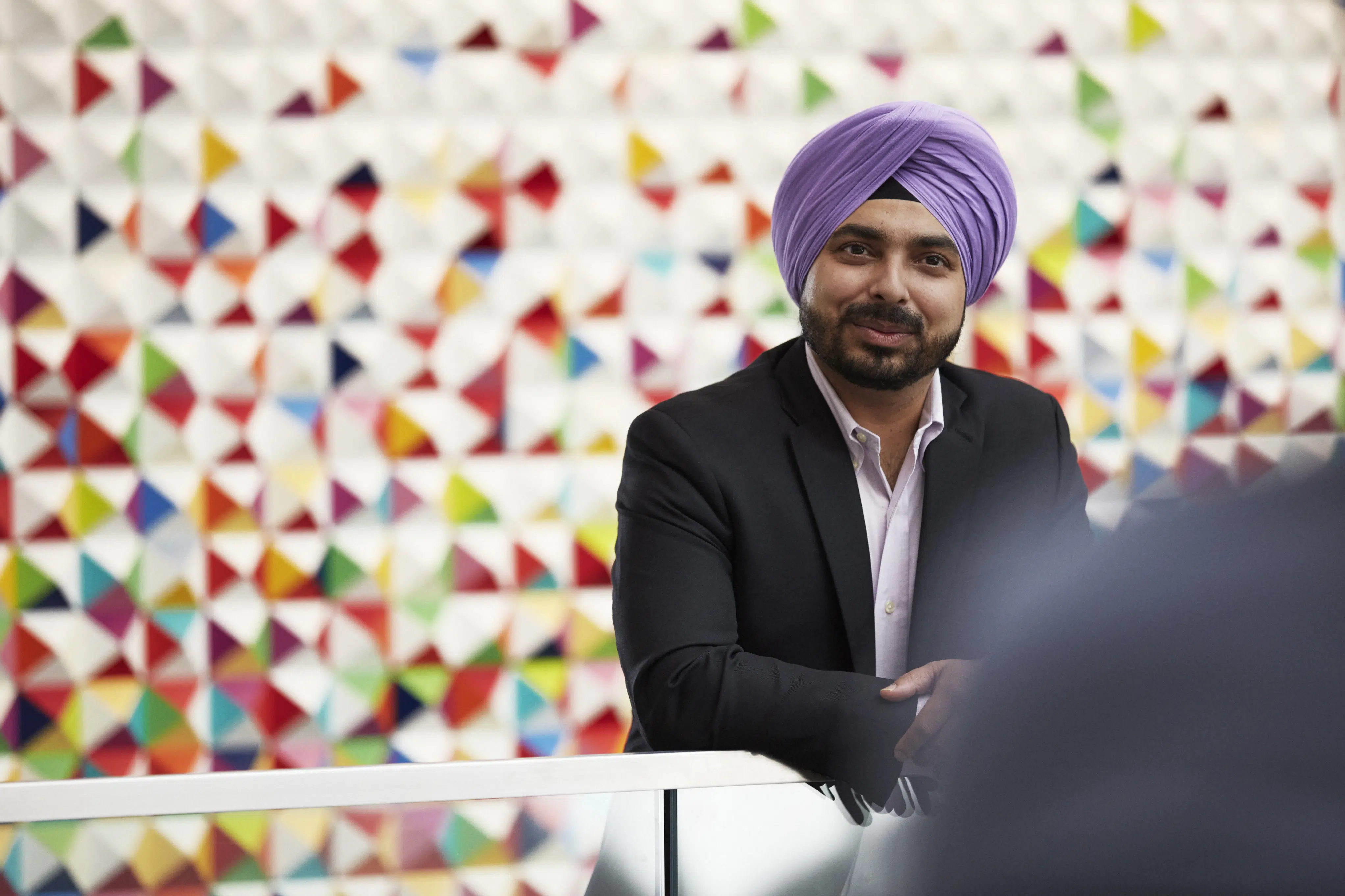 A man in a turbin and suit jacket smiles to camera