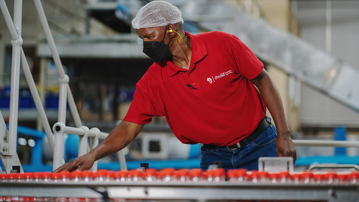 An african-american man works in a bottling line