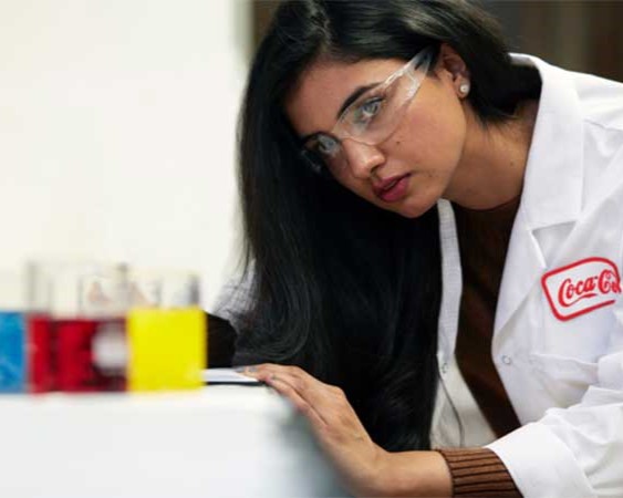 Colors are being analyzed by a technician in a Coca-Cola lab coat