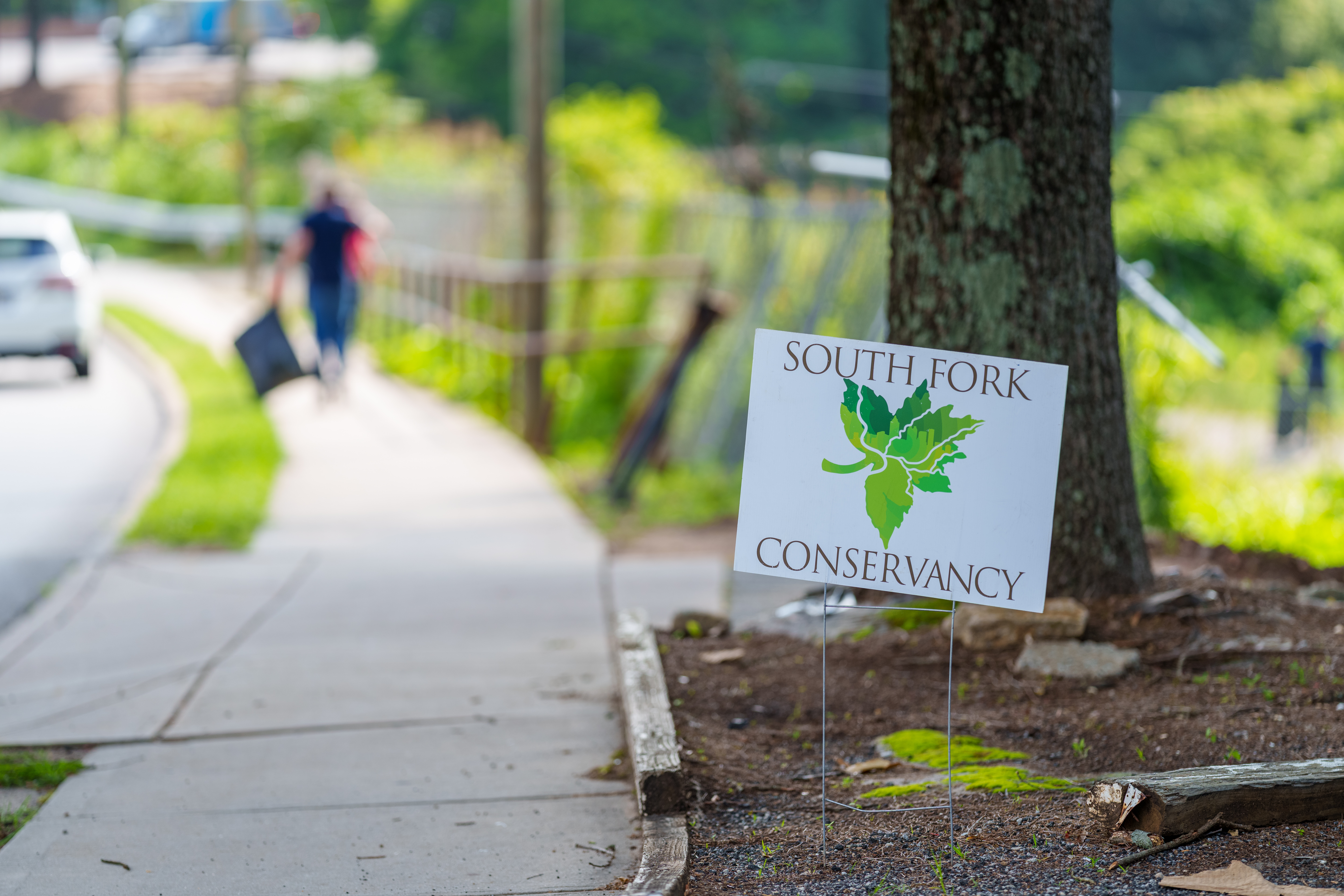 A South Fork Conservancy sign in focus, with the creek blurred in the background