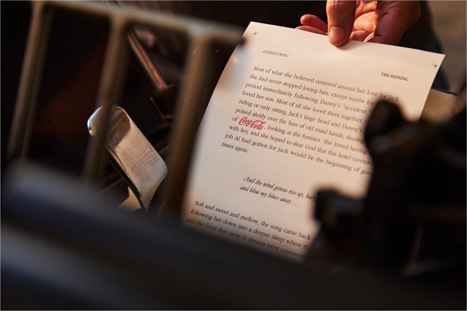 Close up of a hand holding a page from a Steven King novel that mentions Coca-Cola