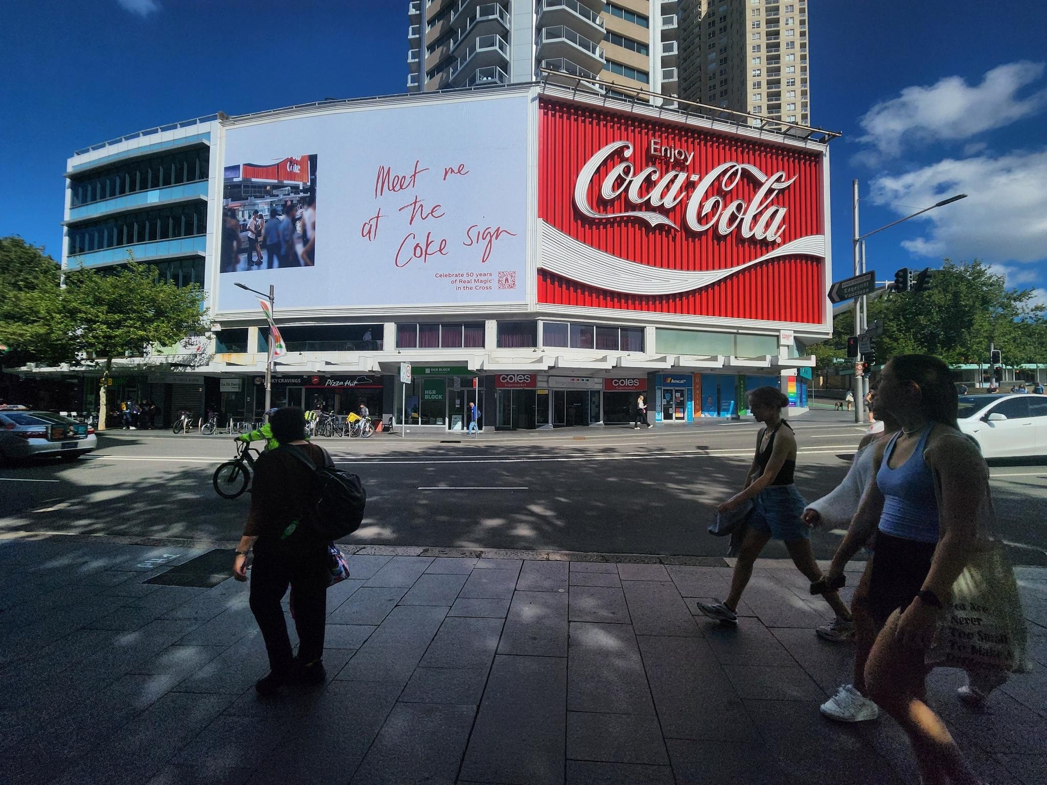 Coca-Cola sign at King's Cross with a billboard beside it saying "Meet me at the Coke sign"