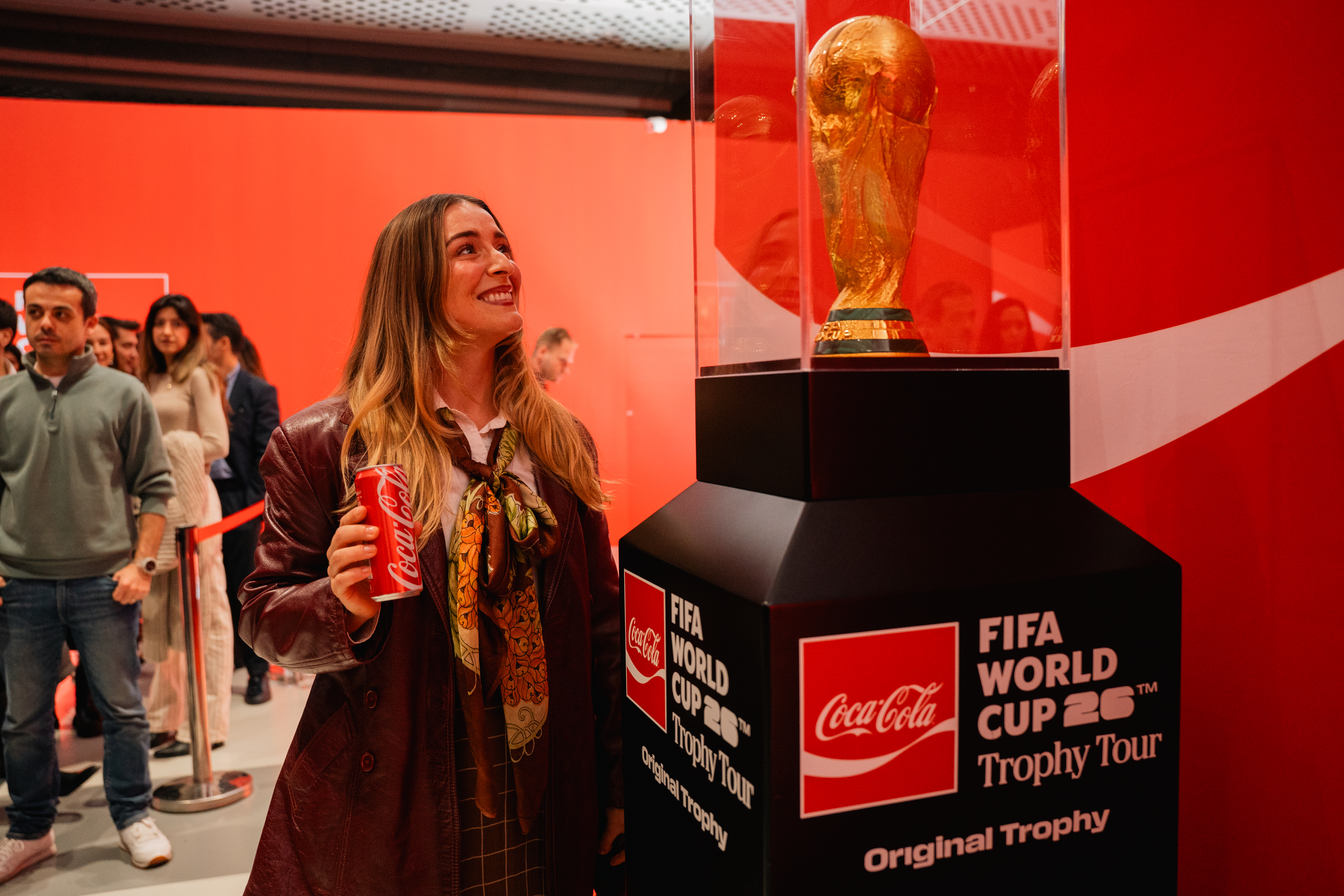 Woman holding can of Coca-Cola viewing FIFA World Cup™ Trophy 