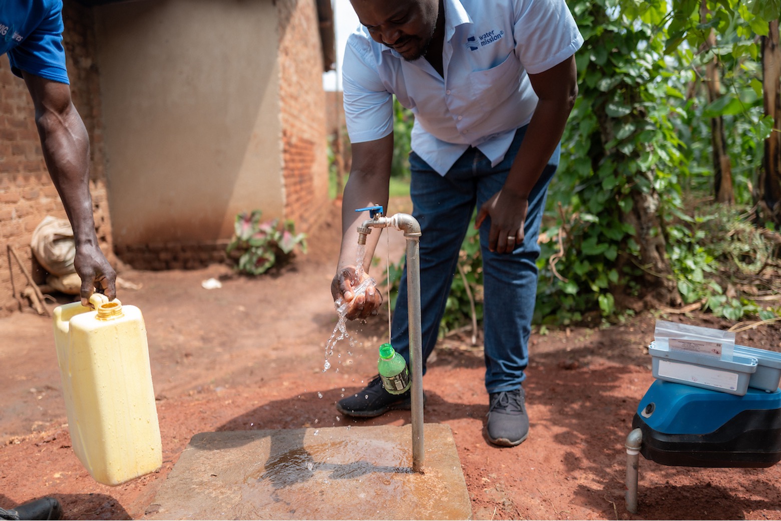 A man getting water from an outdoor fountain.