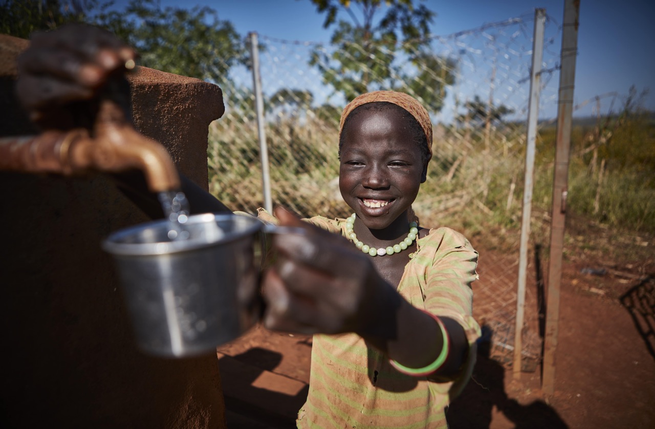 Awogiki fills her cup at one of the new water taps built in her village