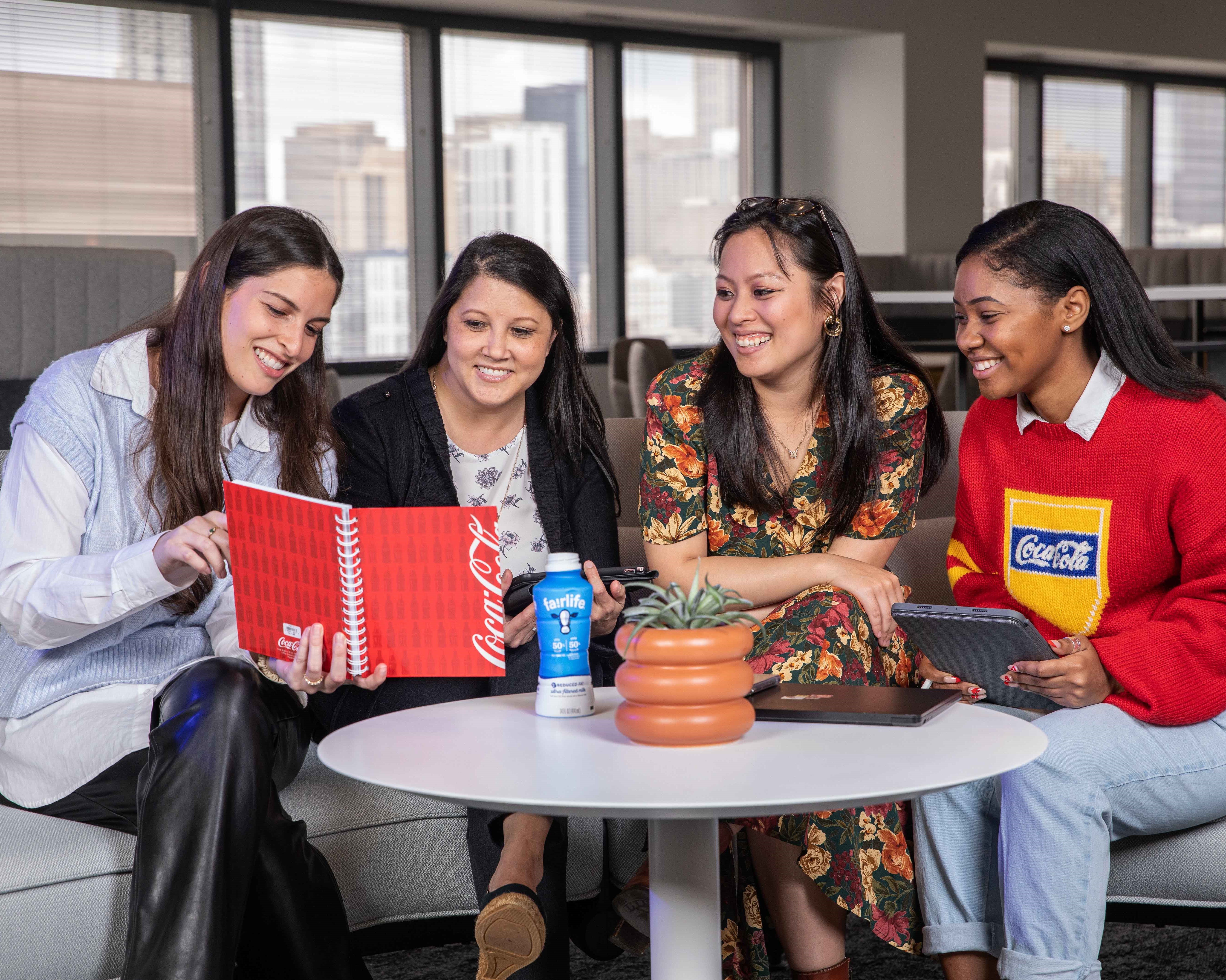 Coca-Cola employees sitting around a small table and looking at a notebook