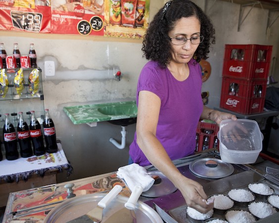 A woman cooking rice with Coca-Cola bottles and a menu in the background