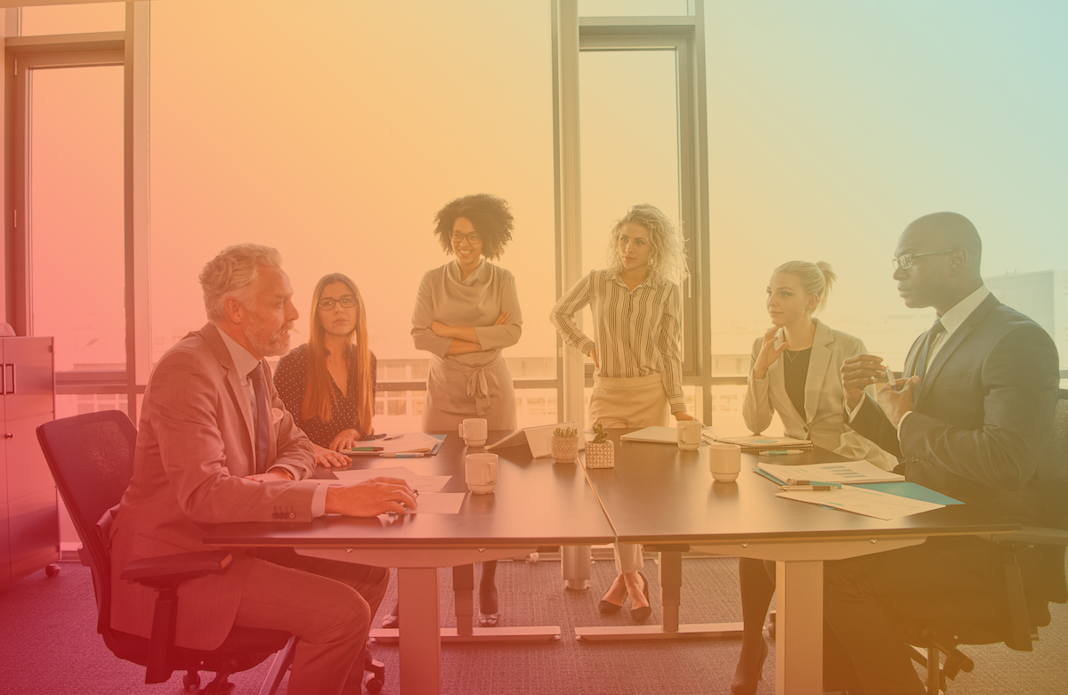 Diverse group of corporate executives talking together around a table during a meeting in a bright modern office