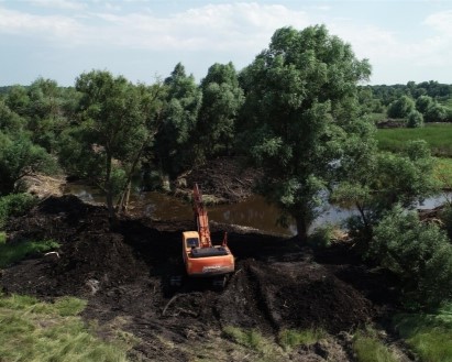 A yellow excavator clears water in Ukraine as part of a USAID project