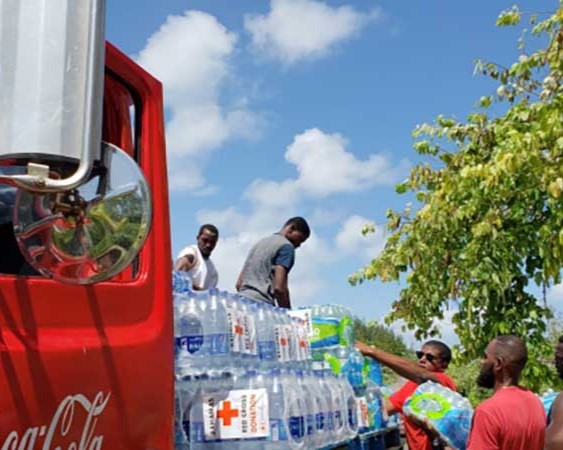A group of men unloading a Coca-Cola truck full of bottled water