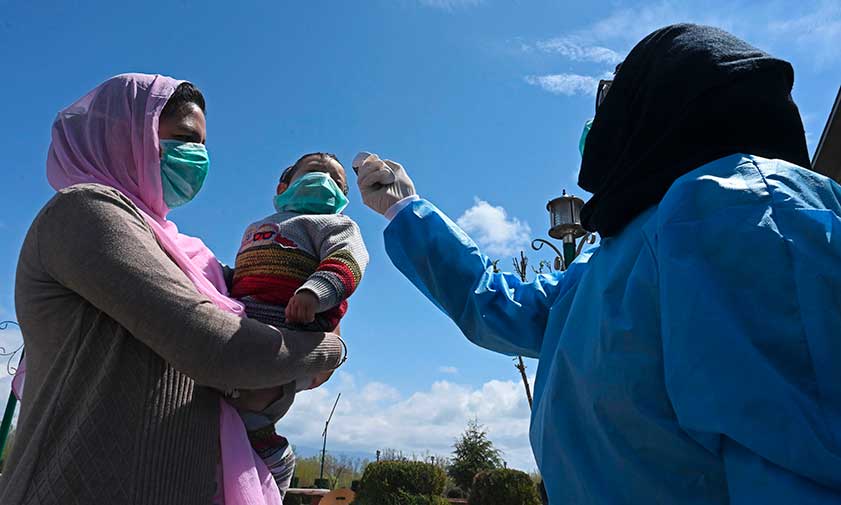 A woman and child in masks getting their temperature checked