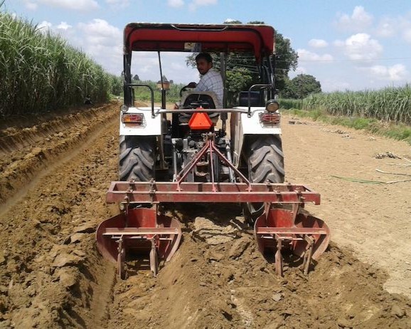 Farmer driving farming machinery to plow soil