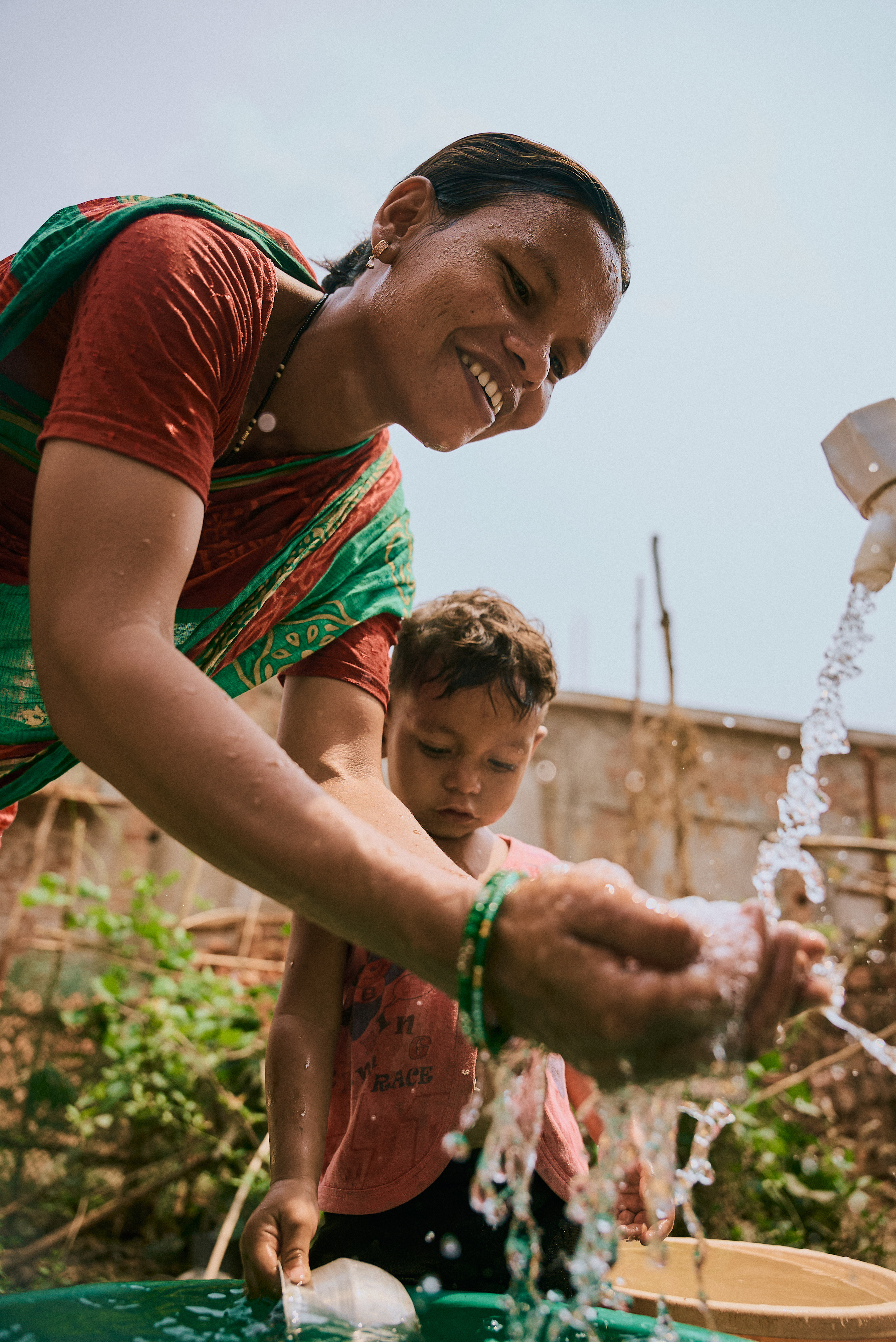 Mother and child receive fresh water from a fountain