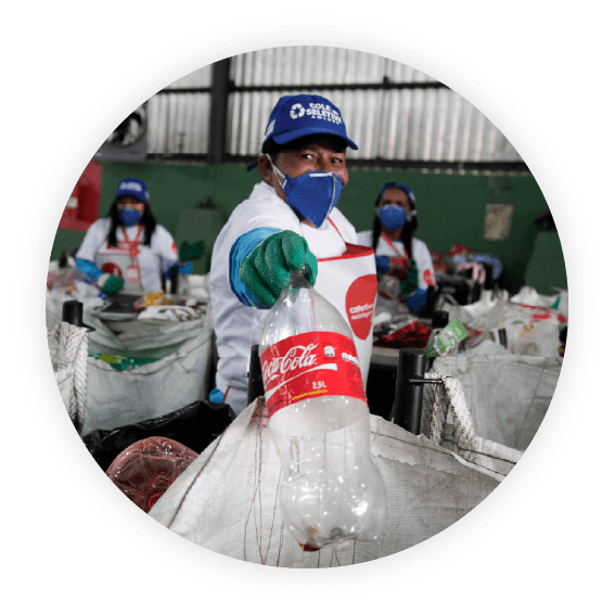 Recycling plant employee holds plastic Coca-Cola bottle
