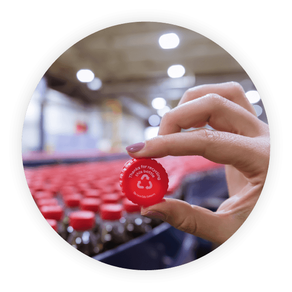 Woman holds red Coca-Cola bottle cap with recycling message